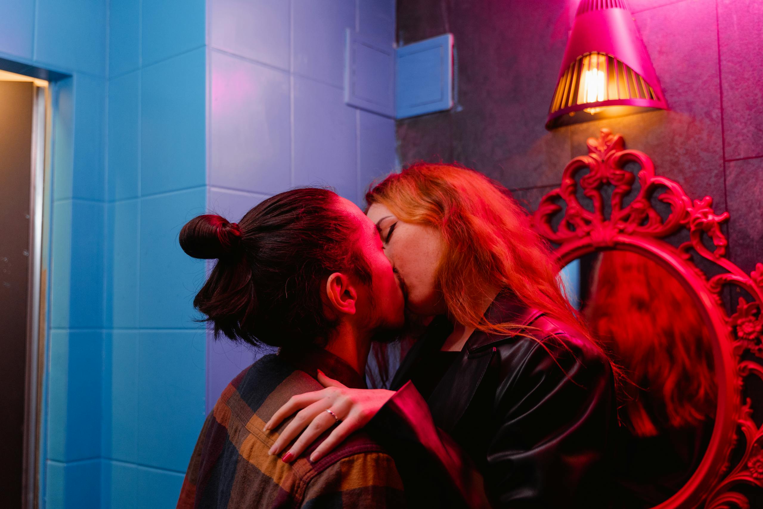 A couple shares a passionate kiss in a vibrant nightclub with colorful lighting. 7271785 scaled