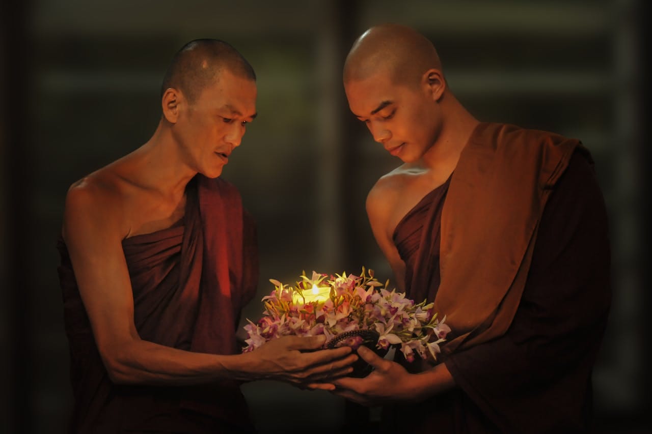 Services Two monks holding a candle surrounded by flowers, symbolizing spirituality and tradition.
